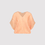 Peach-colored pleated blouse on a light gray background