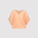 Peach-colored pleated blouse on a light gray background