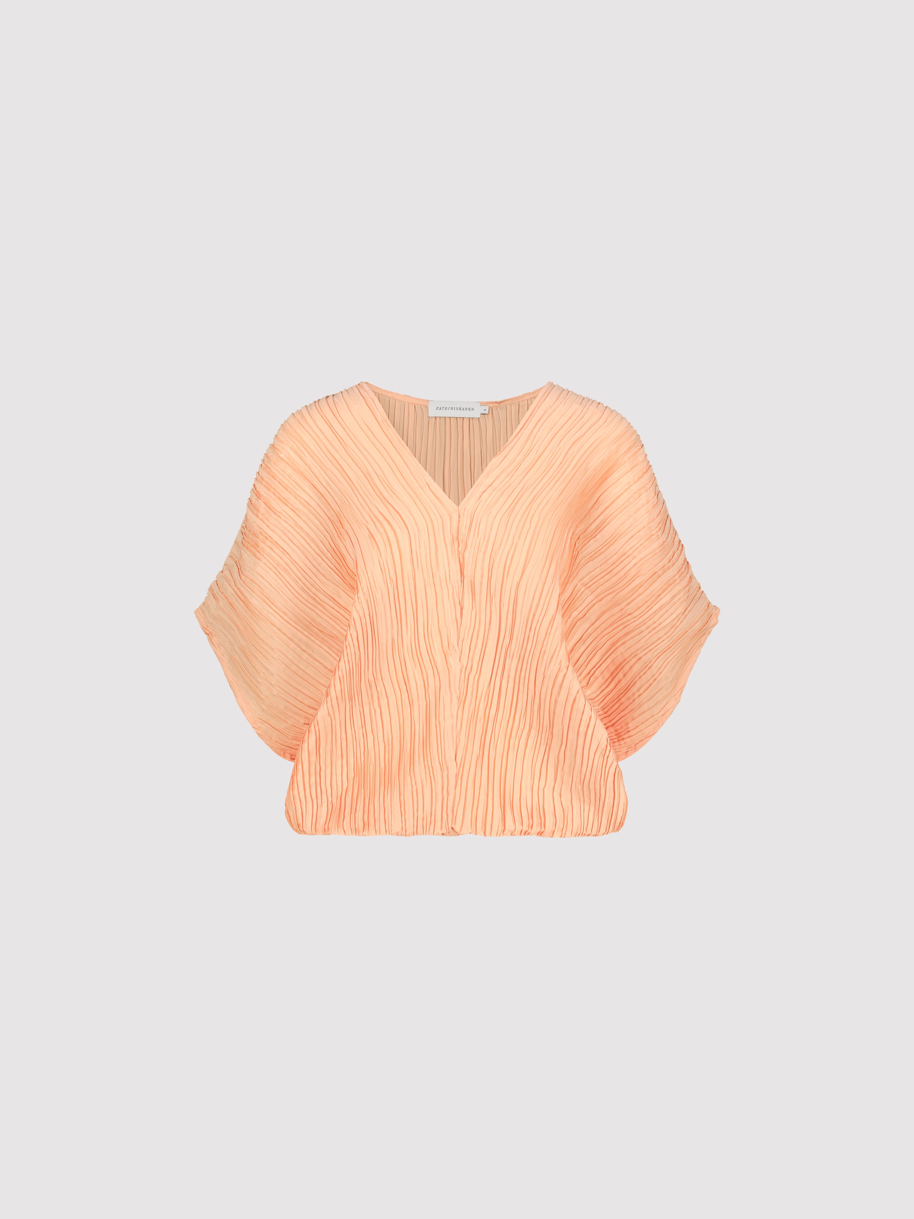 Peach-colored pleated blouse on a light gray background